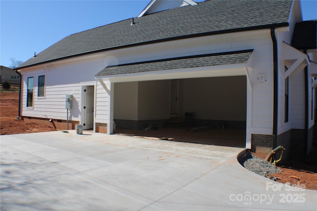 back of property with a shingled roof, crawl space, and driveway