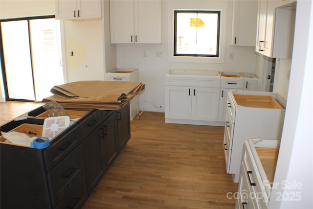 kitchen featuring light wood-style floors, white cabinetry, and dark cabinetry