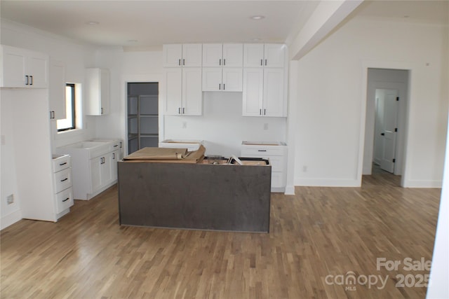 kitchen with light wood-style floors, a kitchen island, and white cabinetry