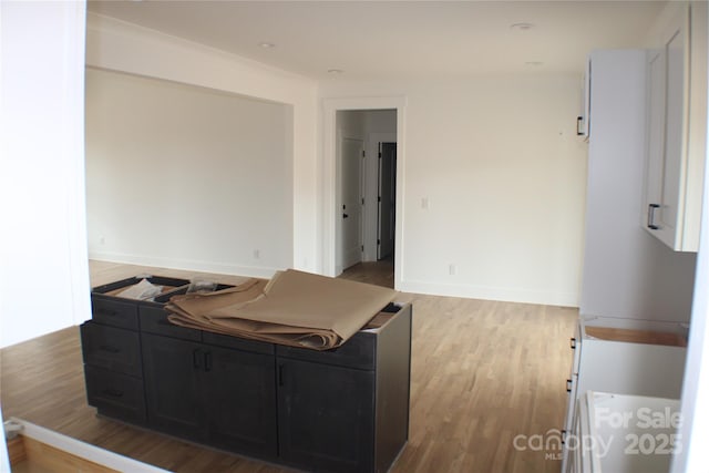 kitchen featuring dark cabinets, light wood-style flooring, and baseboards