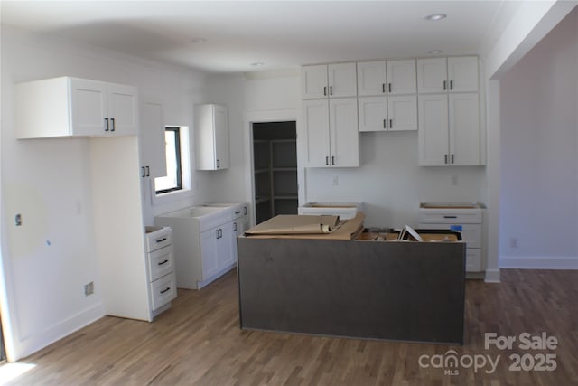 kitchen with a center island, white cabinetry, light wood-style flooring, and baseboards