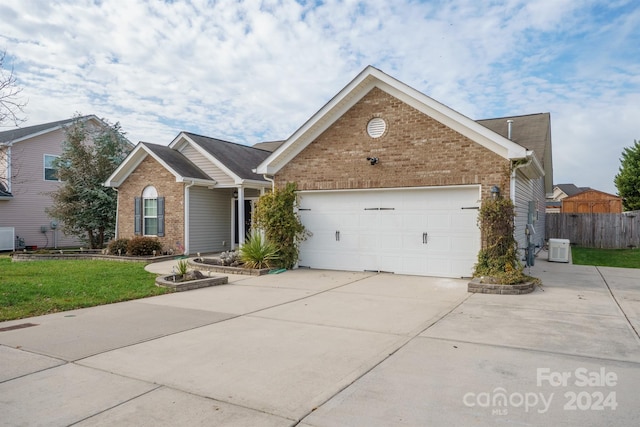 view of front of property featuring cooling unit, a garage, and a front yard