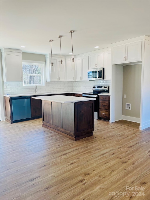 kitchen featuring a center island, white cabinets, stainless steel appliances, and decorative light fixtures