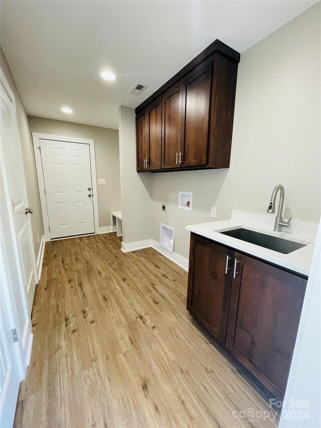 laundry room featuring cabinets, washer hookup, electric dryer hookup, sink, and light hardwood / wood-style flooring