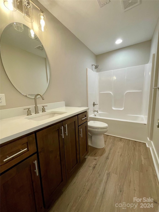 full bathroom featuring hardwood / wood-style flooring, vanity,  shower combination, and toilet