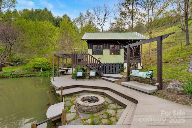 view of dock featuring a fire pit and a deck with water view