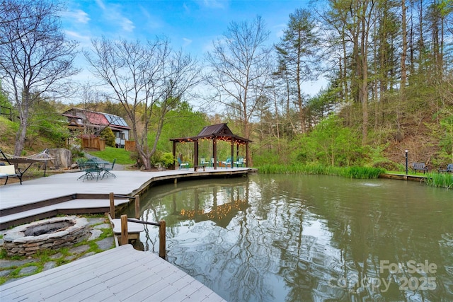 dock area featuring a gazebo, an outdoor fire pit, and a deck with water view