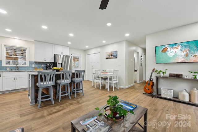 living room featuring ceiling fan, light wood-type flooring, and sink