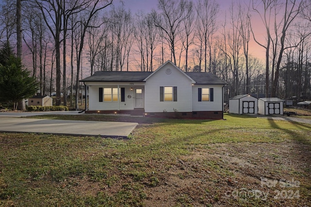 ranch-style house featuring a storage unit, covered porch, and a yard