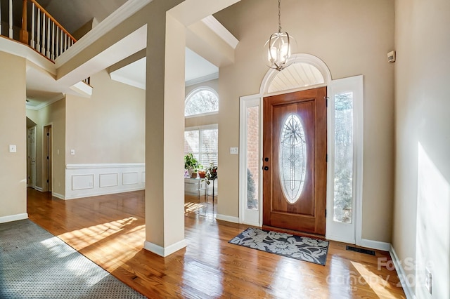 foyer featuring a chandelier, a towering ceiling, light hardwood / wood-style floors, and ornamental molding