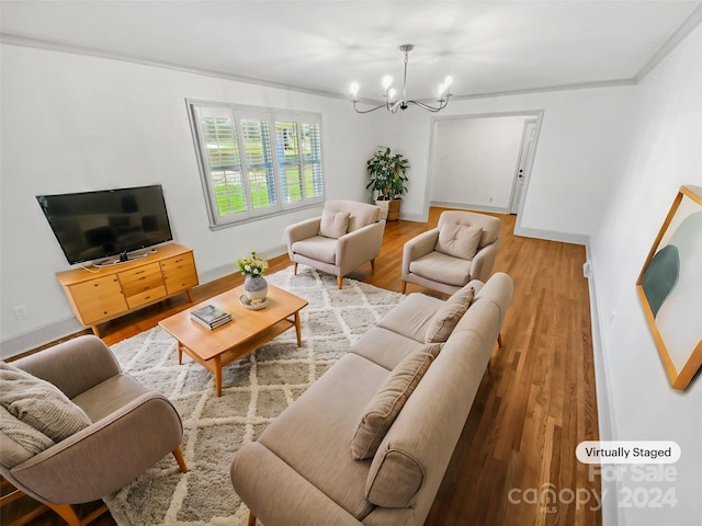 living room with crown molding, wood-type flooring, and an inviting chandelier