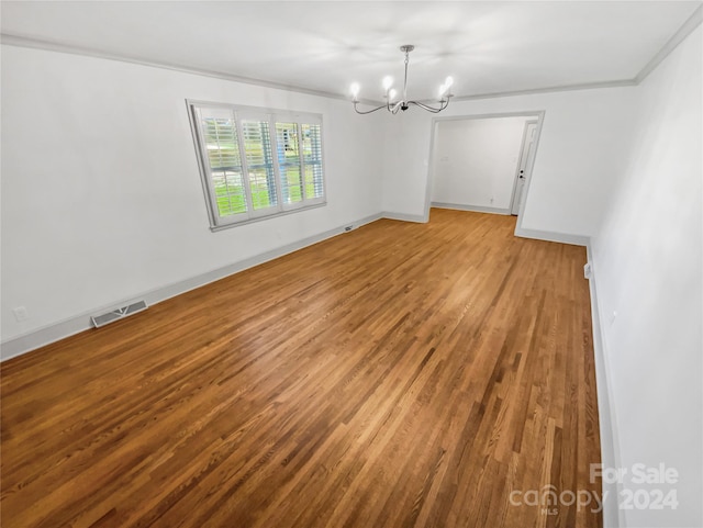 spare room featuring hardwood / wood-style flooring and an inviting chandelier