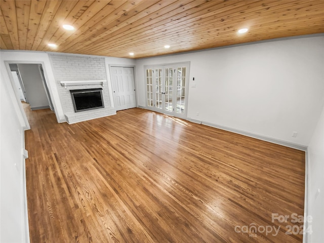 unfurnished living room featuring hardwood / wood-style flooring, a brick fireplace, and wood ceiling