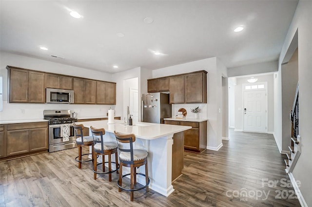 kitchen featuring a kitchen bar, appliances with stainless steel finishes, sink, light hardwood / wood-style flooring, and an island with sink