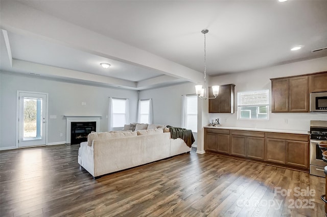 living room featuring dark hardwood / wood-style floors, a raised ceiling, and a chandelier