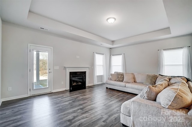 living room with dark hardwood / wood-style flooring and a tray ceiling