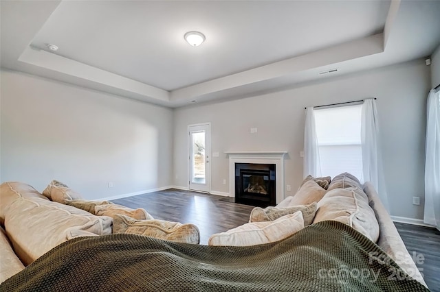 living room featuring a raised ceiling and dark wood-type flooring