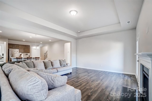 living room featuring a tray ceiling and dark wood-type flooring