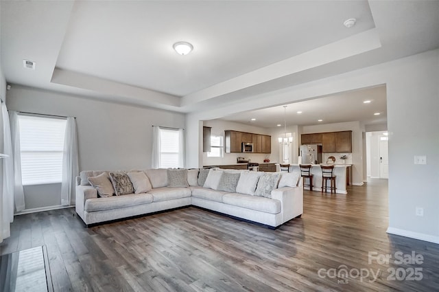 unfurnished living room with a raised ceiling and dark hardwood / wood-style flooring