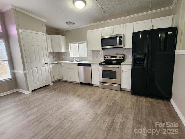 kitchen featuring white cabinets, appliances with stainless steel finishes, decorative backsplash, and light wood-style floors