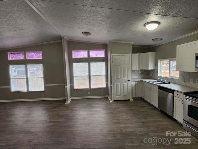 kitchen with white cabinets, a sink, ornamental molding, appliances with stainless steel finishes, and dark wood finished floors