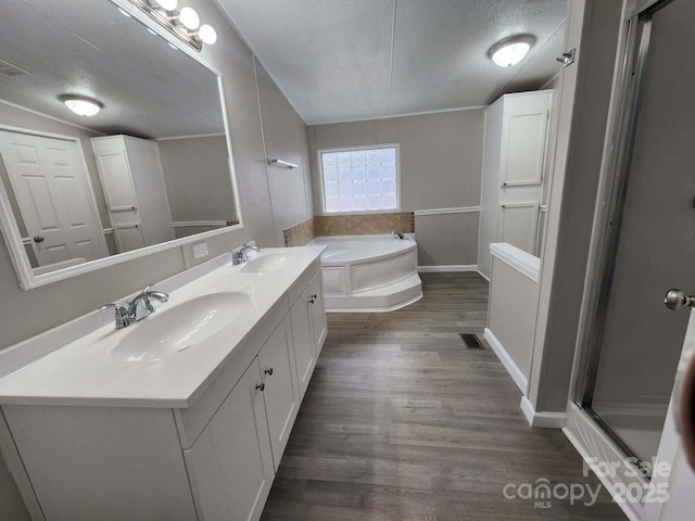 full bathroom featuring a sink, a bath, wood finished floors, and a textured ceiling