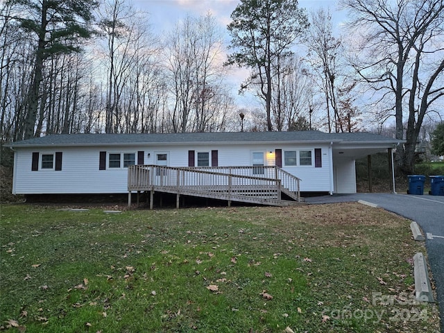 view of front of home with a carport, a deck, and a front yard