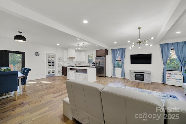 living room featuring beam ceiling, an inviting chandelier, and plenty of natural light