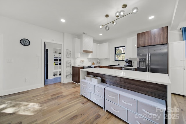 kitchen featuring a center island, white cabinets, stainless steel refrigerator with ice dispenser, light hardwood / wood-style floors, and dark brown cabinetry