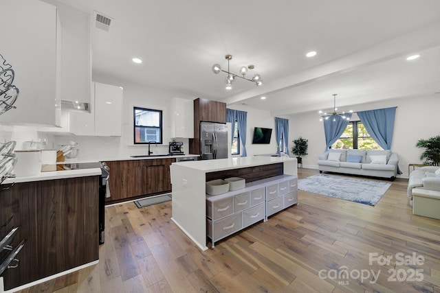 kitchen featuring a center island, an inviting chandelier, stainless steel fridge with ice dispenser, dark brown cabinets, and white cabinets