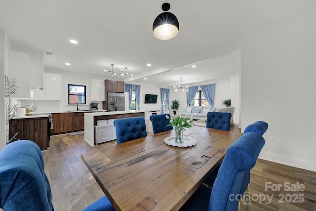 dining area featuring sink, light hardwood / wood-style flooring, and a chandelier