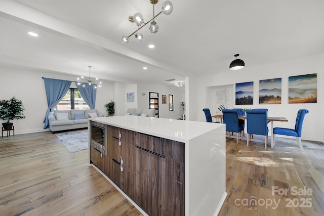 kitchen featuring beam ceiling, light hardwood / wood-style flooring, a kitchen island, and a notable chandelier