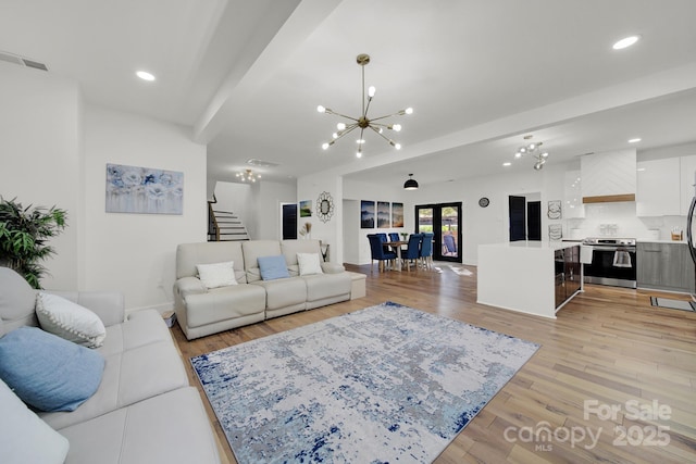 living room featuring beamed ceiling, french doors, light hardwood / wood-style flooring, and an inviting chandelier