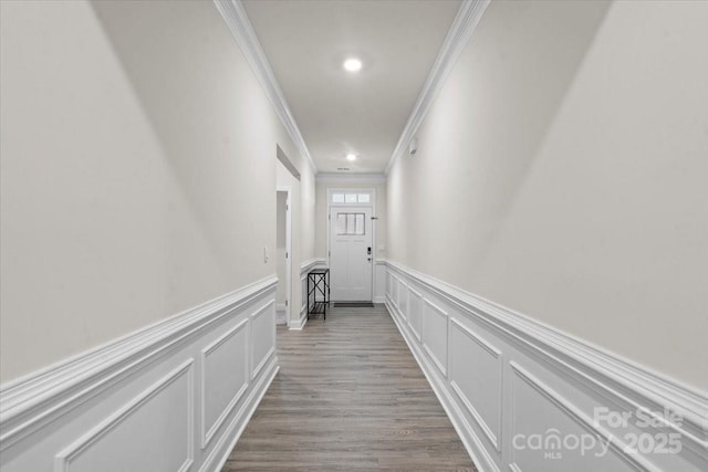 hallway with ornamental molding and light hardwood / wood-style flooring