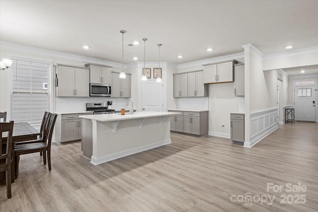 kitchen featuring decorative light fixtures, gray cabinetry, and an island with sink