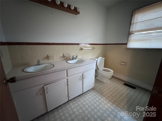 bathroom featuring vanity, toilet, and tile walls