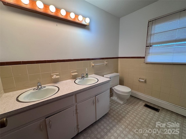 bathroom featuring vanity, toilet, and tile walls