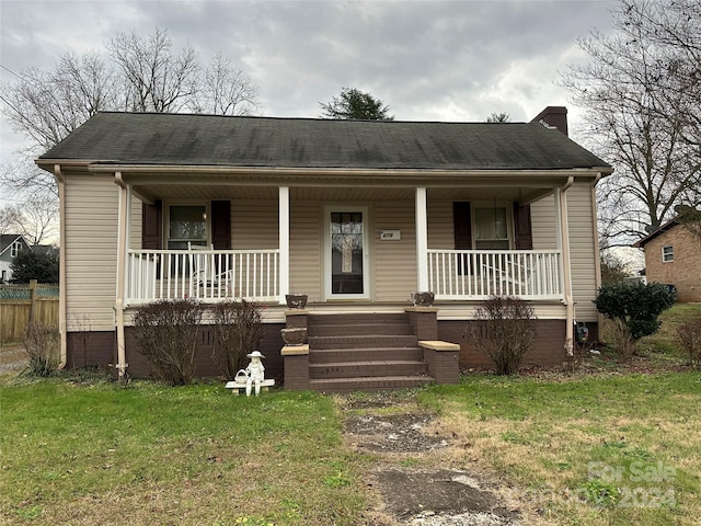 bungalow-style home featuring covered porch and a front lawn