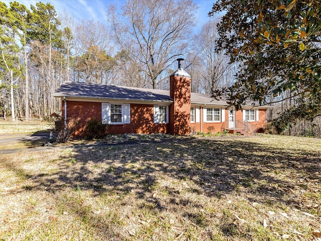 view of front facade featuring brick siding, a chimney, and a front lawn