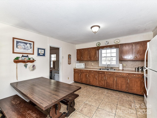 kitchen with light countertops, decorative backsplash, light tile patterned flooring, a sink, and white appliances