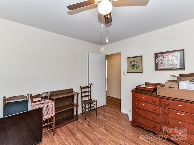 office area with light wood-style floors, baseboards, and a ceiling fan