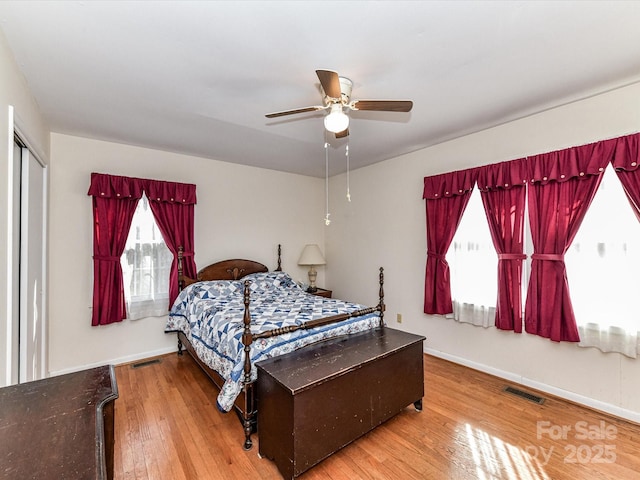 bedroom featuring wood-type flooring, visible vents, ceiling fan, and baseboards