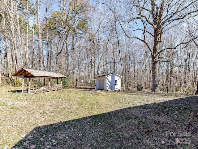 view of yard with an outbuilding, a view of trees, and a storage shed