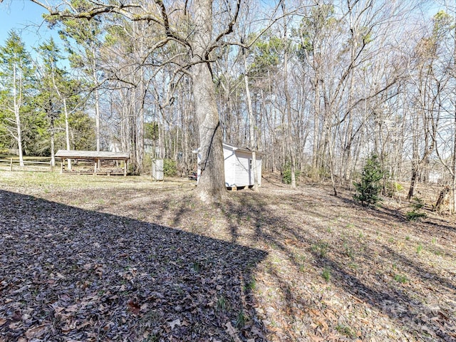 view of yard with a storage unit, a view of trees, and an outbuilding