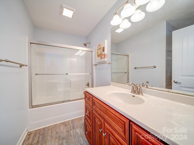 bathroom featuring hardwood / wood-style floors, vanity, and combined bath / shower with glass door