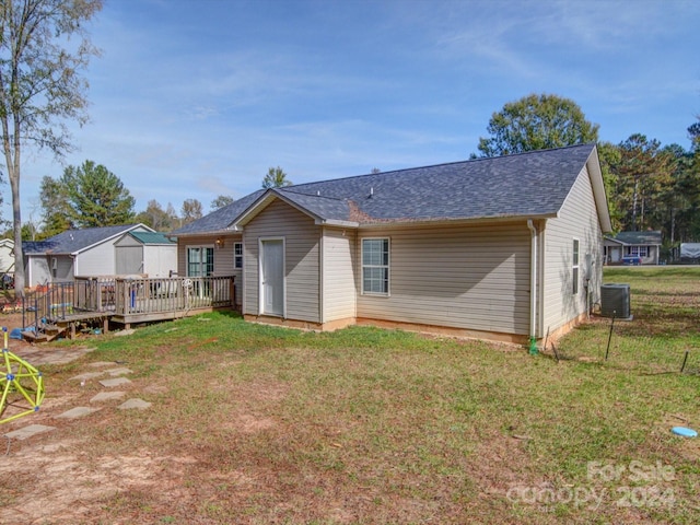 back of house with a deck, cooling unit, and a lawn