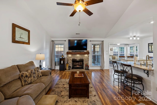 living room featuring ceiling fan, sink, dark hardwood / wood-style flooring, lofted ceiling, and a fireplace