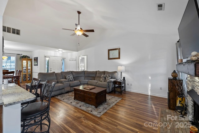 living room with ceiling fan, dark hardwood / wood-style flooring, lofted ceiling, and a fireplace