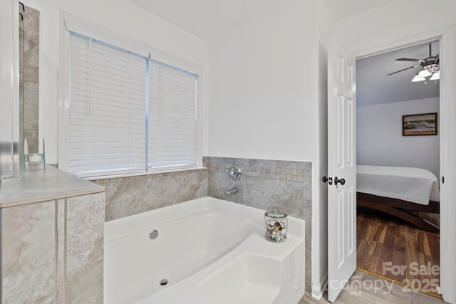 bathroom featuring ceiling fan, wood-type flooring, and a tub to relax in