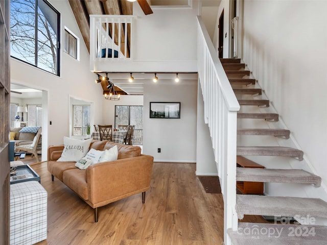 living room with a healthy amount of sunlight, wood-type flooring, a high ceiling, and an inviting chandelier